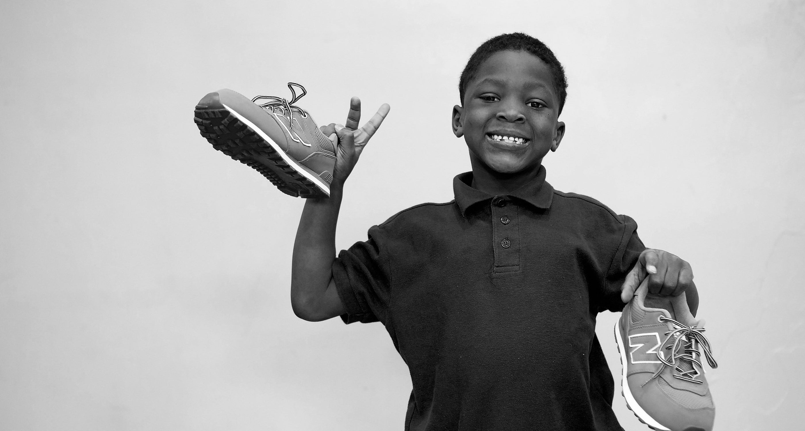 Child holding up New Balance Sneakers for Soles 4 Souls x CANVVS